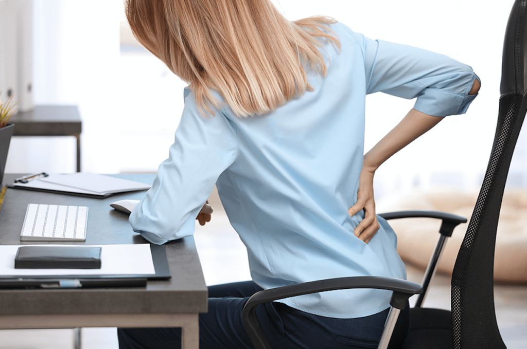 Woman holding low back due to disc bulge pain from sitting