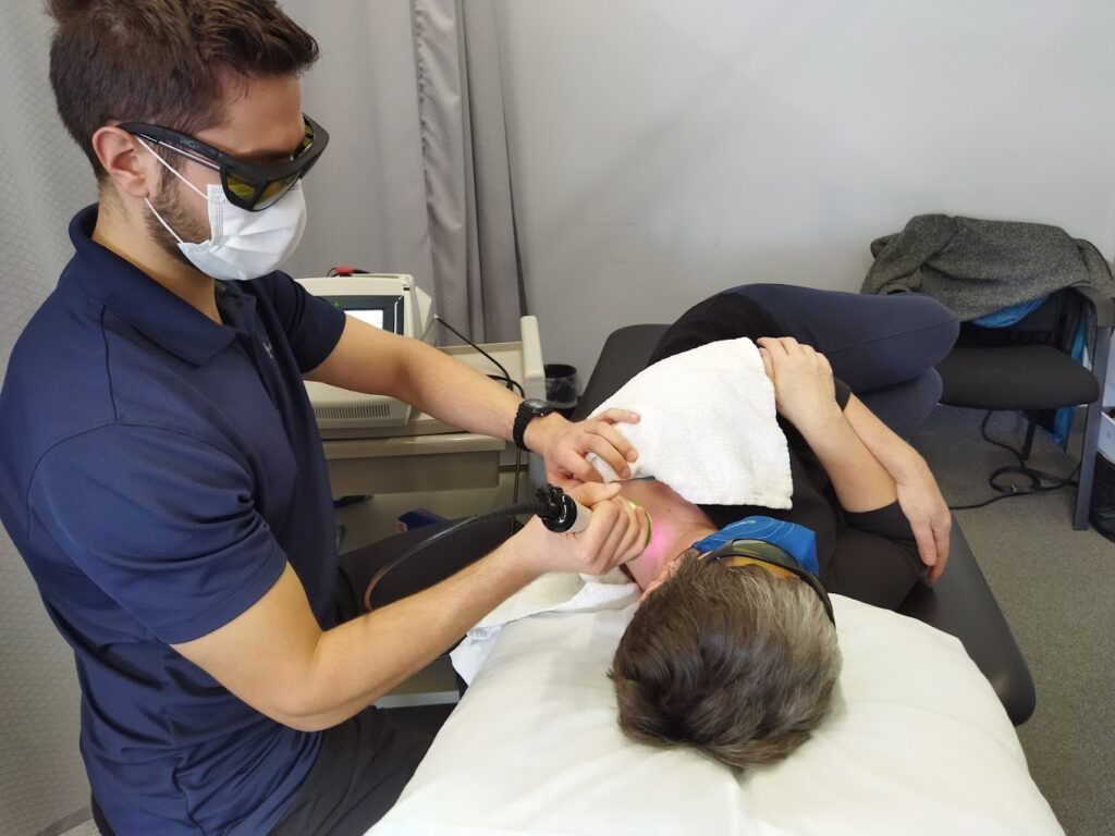Clinician administering class 4 laser therapy to a patient's neck.