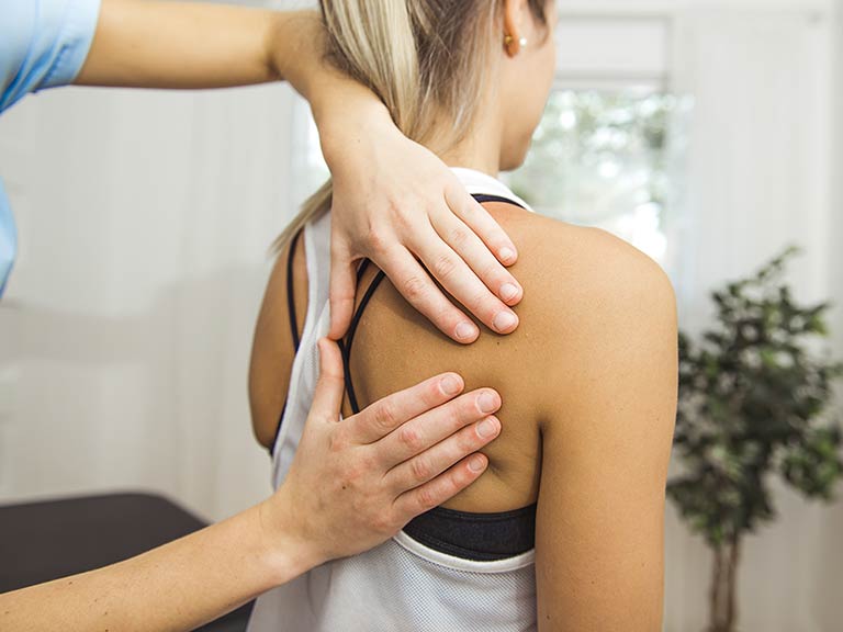 Physiotherapist assessing shoulder and neck of patient
